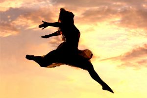 Woman leaping in front of sunset